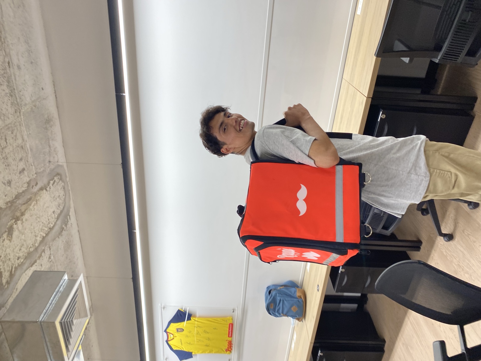 Trying on a Rappi delivery backpack at the office